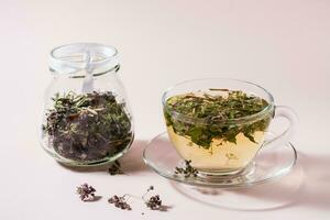 Fresco caliente té con orégano en un taza y seco hierba en un frasco. herbario medicina y alternativa terapia foto