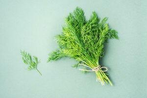 A bunch of fresh dill tied with a rope on a green background. Vitamin greens in a healthy diet. Top view photo