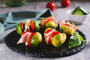 Brussels sprouts, tomatoes, cucumber and bacon sliders on slate board photo