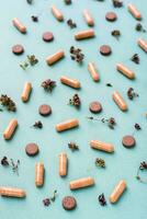 Abstract green background with capsules, pills and herbs. Alternative medicine. Vertical view photo