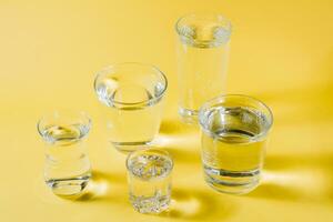 Several glasses of water of different shapes in a yellow-gray palette. Concept of inclusiveness and compatibility. photo