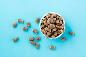 Rye bran in a bowl and on a table on a blue background. Diet and cleansing the body with fiber. Top view photo