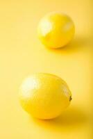 Two ripe whole lemons on a yellow background. Detox fruit diet, body detoxification. Vertical view photo