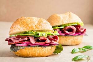 Ready-to-eat hamburger with pastrami, cucumber, radish and herb on craft paper. American fast food. Close-up photo