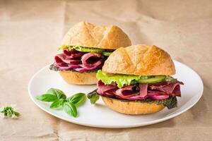 Ready-to-eat hamburgers with pastrami, vegetables and basil on a plate on craft paper. American fast food photo