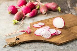 Fresh sliced radish on a cutting board on a wooden table. Vegetables for a vegetarian diet. Rustic style photo