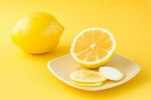 rebanado limón en un platillo y un todo limón siguiente a eso en un amarillo antecedentes. desintoxicación Fruta dieta, cuerpo desintoxicación foto