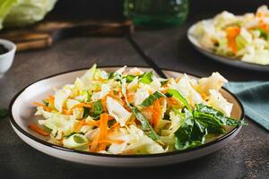 Traditional cole slaw salad of cabbage, carrots and greens on a plate photo