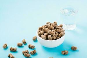 Rye bran in a bowl and on the table and a glass of water on a blue background. Diet and cleansing the body with fiber photo