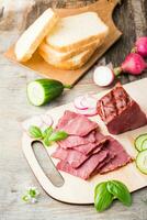 Fresh sliced marbled beef pastrami and vegetables on a cutting board. American delicacy. Rustic style. Vertical view photo
