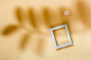 Modern abstract life style background concrete, empty photo frame and stone in soft shadows from leaves. Top view. Place for text