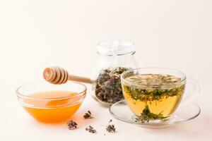 Fresco caliente té con orégano en un taza, miel en un cuenco y seco hierba en un frasco. herbario medicina y alternativa terapia foto