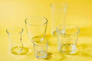 Several empty glasses of different shapes  in a yellow-gray palette. Inclusiveness concept. photo