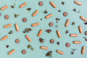 Abstract green background with capsules, pills and herbs. Alternative medicine. Top view photo