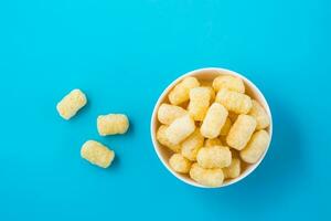 Corn sticks in powdered sugar in a bowl on a blue background. Top view photo