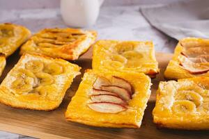 Small upside-down puff pastry tarts with apple and banana on the board photo