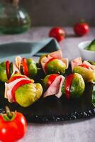 Brussels sprouts, tomatoes, cucumber and bacon sliders on slate board vertical view photo