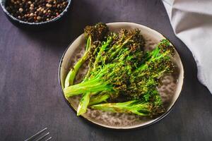 Roasted fresh broccoli sprouts in oil on a plate on the table photo