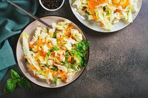 Traditional cole slaw salad of cabbage, carrots and greens on a plate top view photo