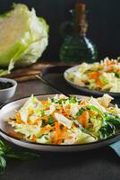 Traditional cole slaw salad of cabbage, carrots and greens on a plate vertical view photo