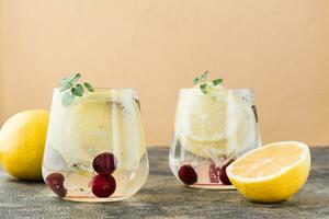 verano refrescante frío cóctel con limón y Cereza - difícil agua de Seltz en lentes en el mesa foto