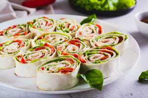 italiano arrollado emparedados con lechuga, jamón y horneado pimientos en Agave un pan en un plato foto