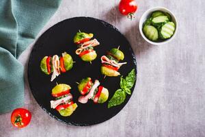 Brussels sprouts, tomatoes, cucumber and bacon sliders on slate board top view photo