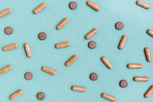 Abstract green background with herb capsules and pills. Alternative medicine. Top view photo