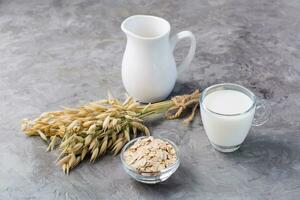 Oat milk in a cup, oatmeal and ears of corn on the table. Alternative to cow's milk. Healthy eating photo