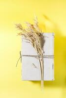 Old books and dry ears of corn tied with rope in yellow and hard light. Wellness, harmony, inclusiveness. Top and vertical view photo