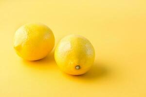 Two ripe whole lemons on a yellow background. Detox fruit diet, body detoxification photo