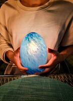 man holding blue light on two hand. magician use mineral stone predict fortune future in dark night. photo