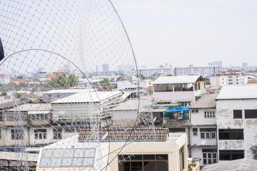 Install plastic net for protect pigeon bird in balcony apartment. Professional service man setup netting birds for clean and hygiene. Isolated on blue sky and high building background photo