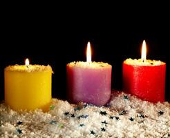 Three candles with artificial snow. photo