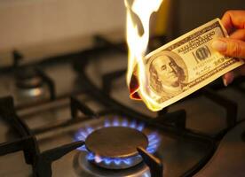 The american dollar is burning in the fire. Burning gas burner on the background of one hundred dollars. The concept the rise in the price of gas in USA. Expensive gas supply. photo