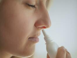 un mujer con un líquido nariz sostiene un medicina en su mano. foto