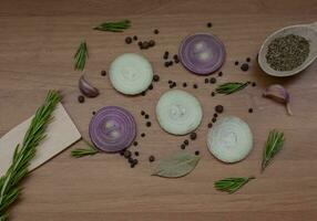 Flat lay composition with red onion rings and spices on a wooden background. photo