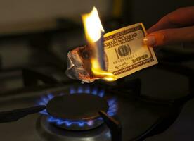 The American dollar is on fire. Burning gas burner on the background of one hundred dollars. The concept of gas price increase. Expensive gas supply. Selective focus. photo