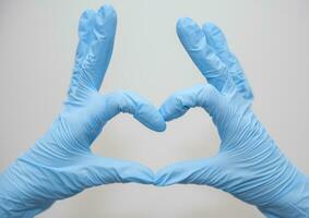 Doctor's hands in medical gloves in heart shape with copy space photo