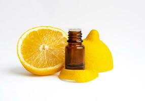 Glass bottle of lemon essential extract aroma oil and fresh organic limon fruit with slice isolated on white background photo