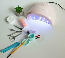 A set of manicure tools scissors for a haircut and a cuticle pusher and a  lamp for drying shellac on nails. photo