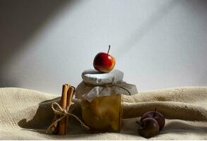 Apple jam in a transparent glass jar. Jam from apples and orange on a light background. Delicious marmalade photo