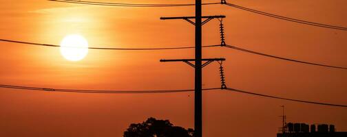 High voltage electric transmission pylon. High voltage power lines against sunset sky. Electricity pylon and electric power transmission lines. High Voltage pole provide power supply. Energy crisis. photo