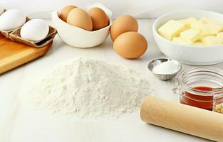 Baking ingredients including dough, eggs, flour, sugar, and butter with a rolling pin on a white kitchen background. photo