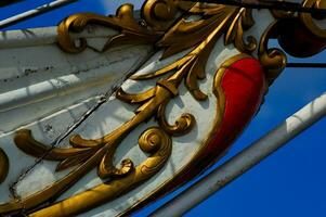 detail of a historic sailing vessel with golden floral ornament on a white background on a sunny day photo