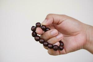 Close up hand holds beads bracelet, counting for doing meditation.Concept, fashion accessories. Religious amulet for luck, can be used in doing meditation or praying ritual. Culture of faith. photo