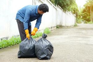 asiático hombre es que lleva negro basura pantalones a lanzar a disposición vertedero concepto, desperdiciar, basura gestión. familiar, quehaceres en diario rutina a mantener basura lejos. foto