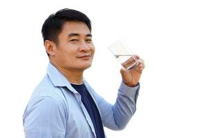 Handsome Asian man holds transparent glass of water to drink, isolated on white background. Concept, drinking water for health at least 8 glasses a day. Health care.  Healthy lifestyle. photo