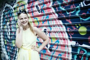 Woman chatting on her mobile in front of graffiti photo