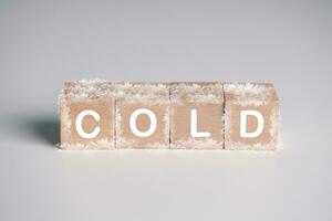 wooden cube block with text COLD and ice crystal. temperature, weather and environment concept. photo